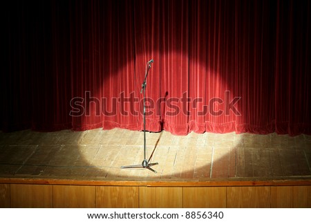 microphone on wooden stage, red curtain in background, spot light