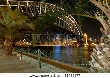 night scene of sydney landmarks; harbour bridge, opera house, sydney cbd, palms in foreground