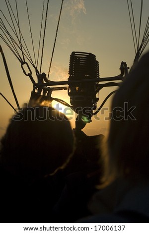 black silhouettes of people in an hot air balloon, burner with fire