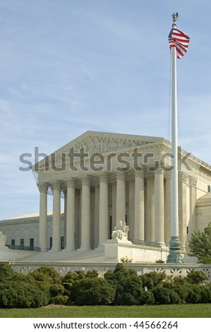 The front of the US Supreme Court in Washington, DC. American flag on a mast in foreground.
