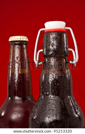 wet brown beer bottles in front of a red background.