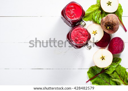 Red smoothies from beetroot, beet leaves and apple on white wooden table with copy space. Flat lay.