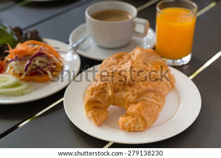 Croissant Breakfast served with black coffee and a breakfast menu, such as orange juice, jam, eggs, filling it.