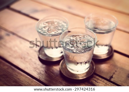 Drinking cold water into a  three glass placed on the wooden table.