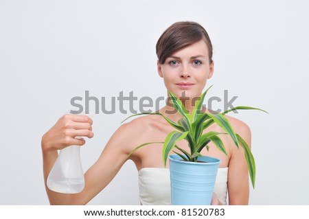 Young lady watering green plant in a blue basket