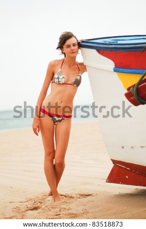 Slim girl in bikini  near the old boat on the beach