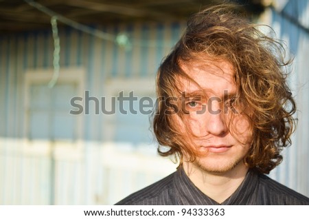 a portrait lifestyle shot of a young guy with long hair in the wind