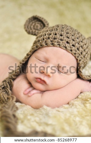 Sleeping newborn baby on fur with knitted teddy bear hat