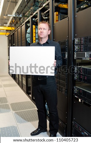 Business man with a contemplative look holding a white board in a datacenter.