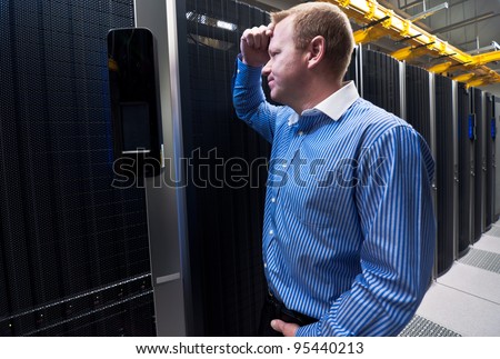 Business man in a data center looking frustrated with the current system. He is looking for a better IT solution.