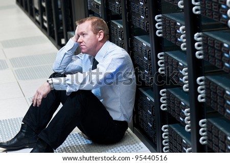 Business man sitting in a data center looking frustrated with the current system. He is looking for a better IT solution