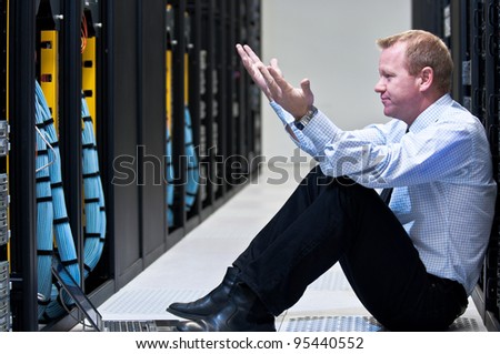 Business man sitting in a data center looking frustrated with the current system. He is looking for a better IT solution