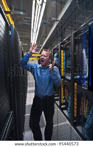 Man looking astonished in a network data center. Shot through a hexagonal door grille
