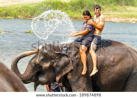 CHIWAN, NEPAL - APRIL 10,2013-couple are enjoying water splashing by the elephant at the chitwan national park.Chiwan was famous national park for wildlife.