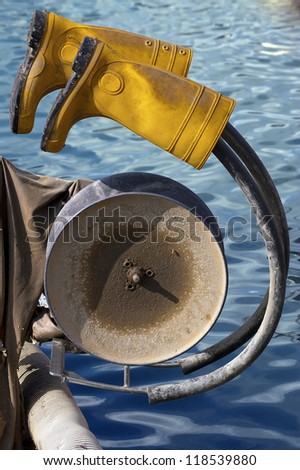 Fisherman\'s Rest / Yellow rubber boots hanging on to fishing winch - concept of fisherman\'s rest