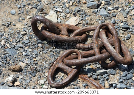 Old and Abandoned Rusty Chain / Old rusty chain for mooring abandoned on the ground with gravel