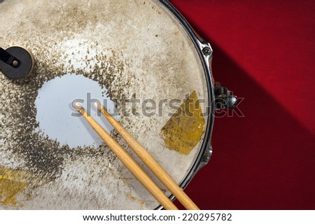 Old Metal Snare Drum with Drumsticks / Close up of metallic and old snare drum with wooden drumsticks on dark red velvet background
