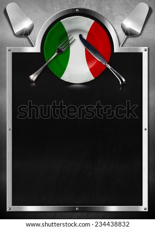 Empty blackboard on metallic background with empty plate colored with the colors of Italian flag, silver cutlery and kitchen utensils. Template for recipes or Italian food menu