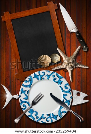Seafood Menu Background / Restaurant seafood menu with metal fish, empty blackboard, empty plate with silver cutlery, starfish, seashells and kitchen knife on wooden background