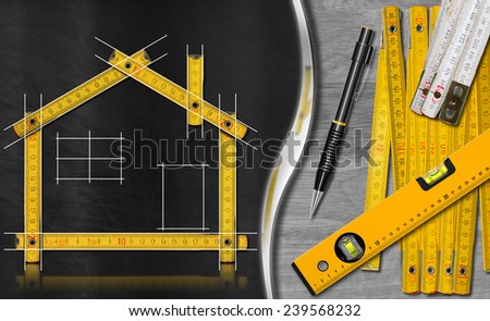 House project concept. Wooden meter ruler in the shape of house with a drawing, propelling pencil, two meter tools and spirit level on a blackboard and wooden background