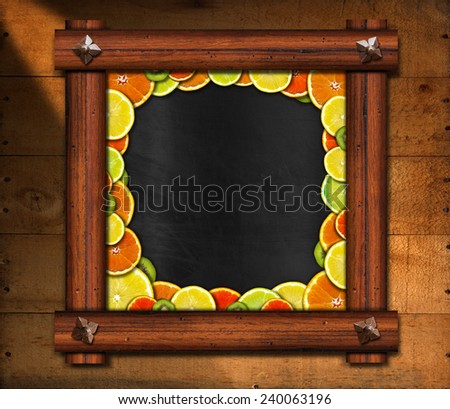 Blackboard with Wooden Frame and Fruit. Blackboard with wooden frame and ancient nails with oranges, lemons and kiwi on wooden background