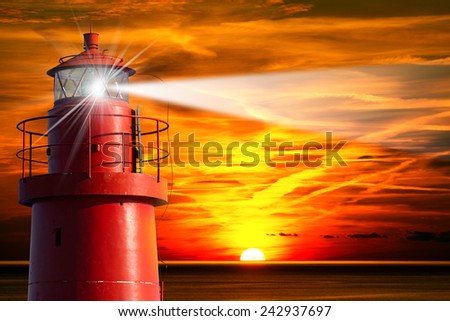 Red Lighthouse with Light Beam at Sunset. The top of a red and metallic lighthouse with light beam at sunset with clouds