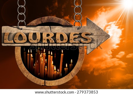 Lourdes - Sign with Votive Candles at Sunset. Pilgrimage wooden directional sign of Lourdes with an arrow and votive candles. Hanging from a metal chain at sunset with clouds and sun rays