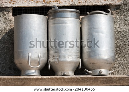 Old Milk Cans Made of Aluminum. Three old milk cans made of aluminum to dry on a wooden bench