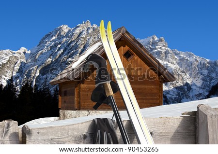 Nordic Skiing in the foreground and Wooden chalet in winter - Alps Italy