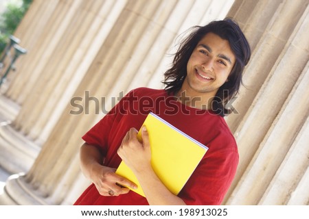 Smiling indian student outdoors with columns at the background