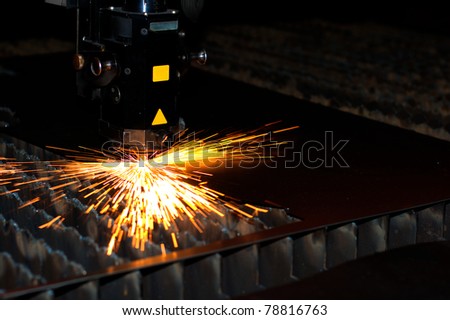 Industrial laser cuts metal with sparks flying around