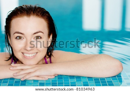 Portrait of beautiful smiling girl in a swimming pool with a copy space