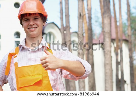 Smiling worker with a thumb up in an orange uniform outdoors with a copy space
