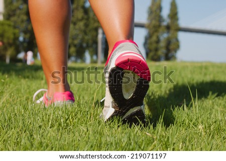 Running shoes closeup - woman running over the grass