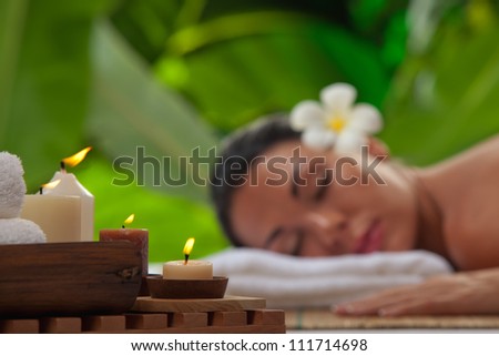 portrait of young beautiful woman in spa environment. blurred face, focused on candles.