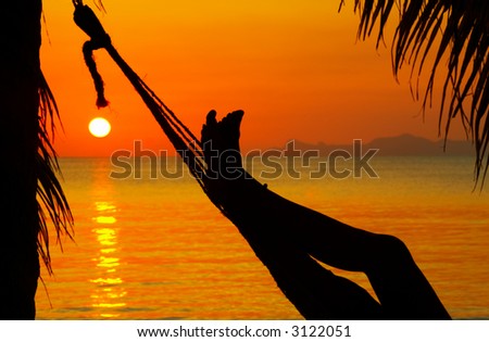 view of a pair of woman’s legs in hammock during sunset