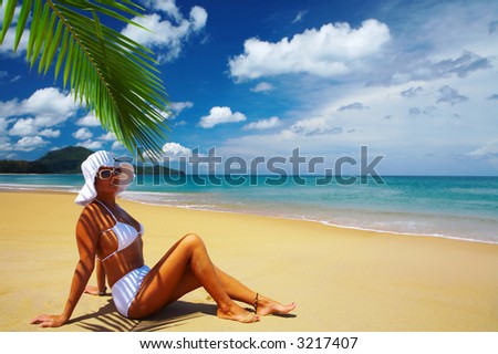 view of nice woman lounging on tropical beach in white panama and bikini