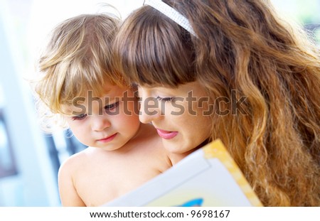 High key portrait  of young mother reading a book for her baby [3 years old]