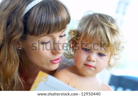High key portrait  of young mother reading a book for her baby . focused on baby’s face