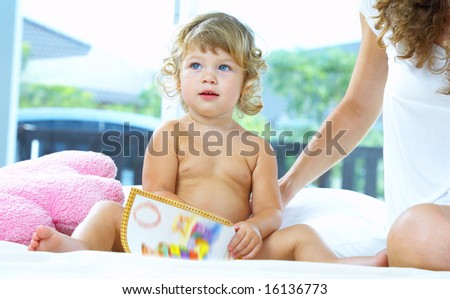 High key portrait  of young baby getting busy with the book
