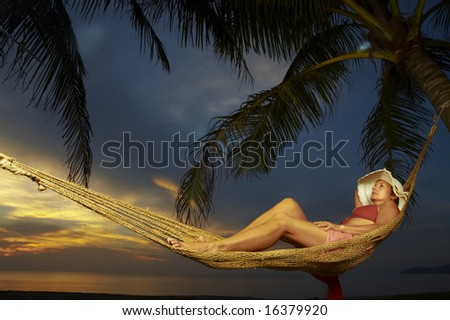 view of a woman lounging in hammock during sunset