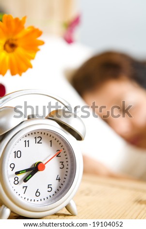 Close up view of  table clock and woman sleeping on back