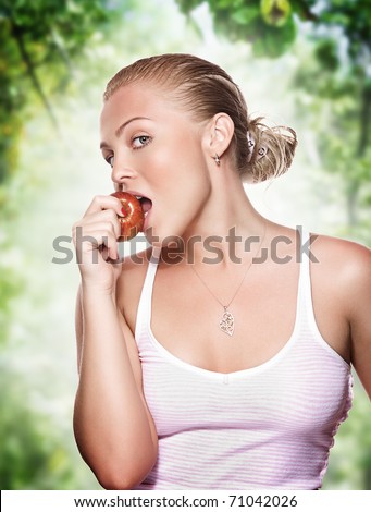 portrait of young beautiful woman biting apple on color back