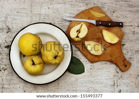 Rural still life ripe yellow quince fruits on the plate and cut fruit on plate with knife