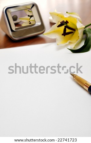 paper, pen, flower and a photo frame on a table