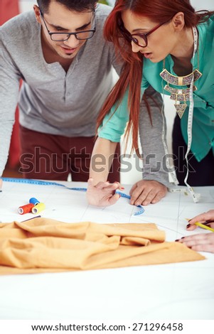 Young clothing designers debating over sewing pattern