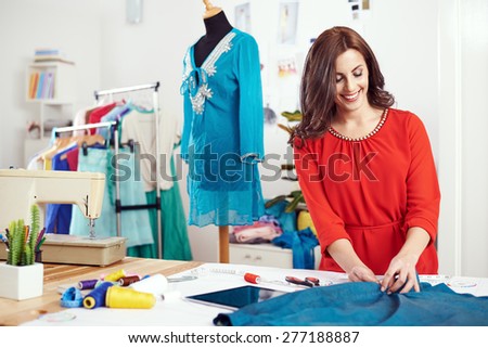 Young female designer measuring textile material