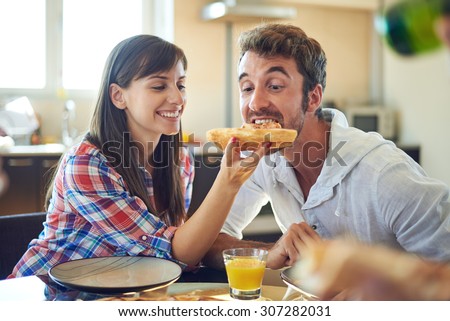 Girl feeding guy with piece of pizza