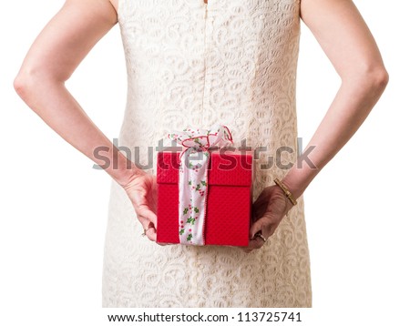 Women in white hiding a Christmas present behind her back.
