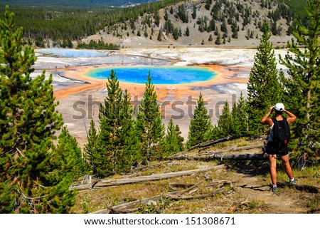 A hiker looking down on Yellowstone National Park\'s Grand Prismatic Spring in Yellowstone National Park, the largest hot spring in the United States, and the third largest in the world.